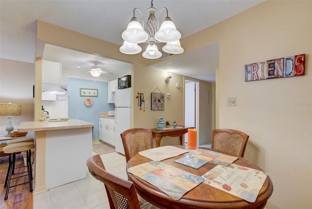 dining room with light tile patterned floors and ceiling fan with notable chandelier