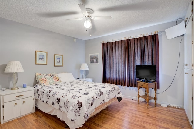 bedroom with ceiling fan, light hardwood / wood-style floors, and a textured ceiling