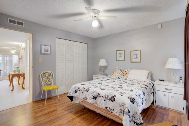 bedroom featuring ceiling fan, light hardwood / wood-style flooring, a textured ceiling, and a closet