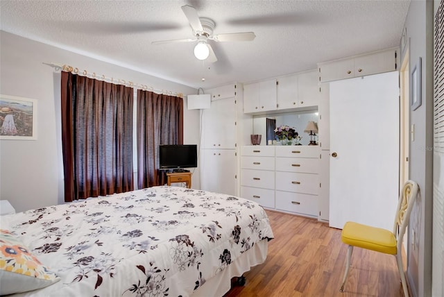 bedroom with ceiling fan, light hardwood / wood-style floors, and a textured ceiling