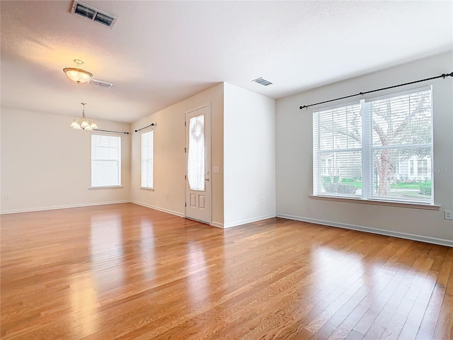 interior space with plenty of natural light, an inviting chandelier, and light wood-type flooring