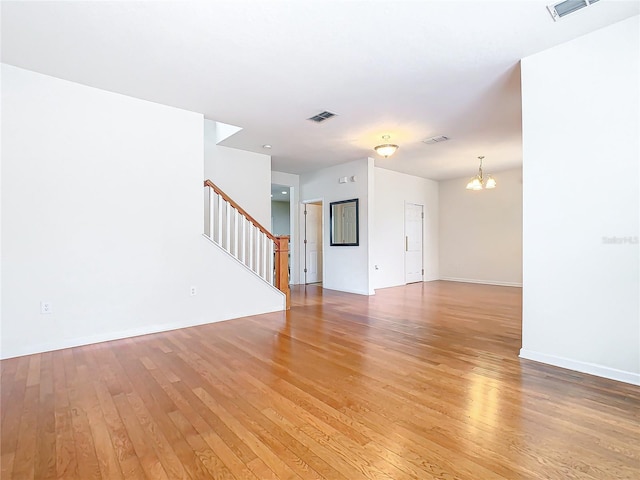 spare room with a chandelier and light hardwood / wood-style flooring