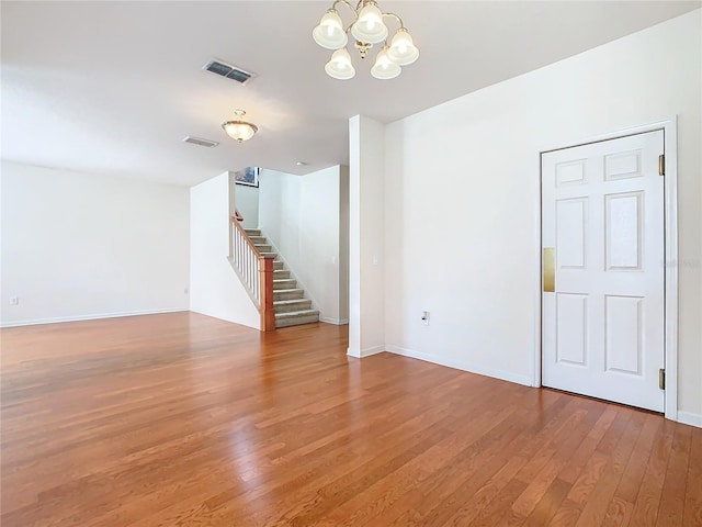 empty room featuring a chandelier and hardwood / wood-style flooring