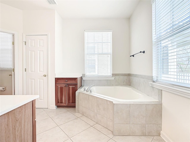 bathroom featuring tile patterned flooring, vanity, and a relaxing tiled tub