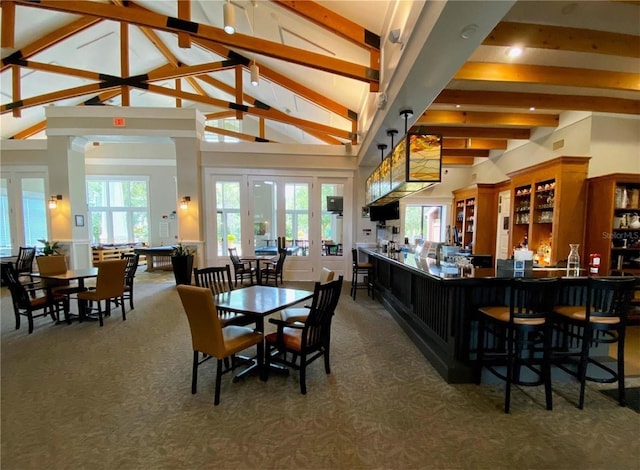 carpeted dining room with beam ceiling and high vaulted ceiling