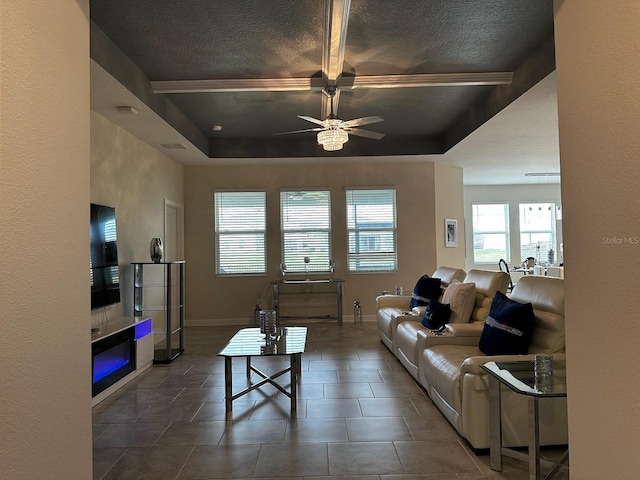 tiled living room with ceiling fan and a tray ceiling