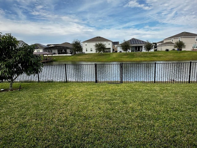 view of yard with fence, a water view, and a residential view