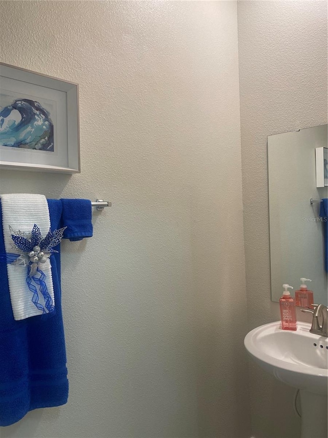 bathroom with a textured wall and a sink