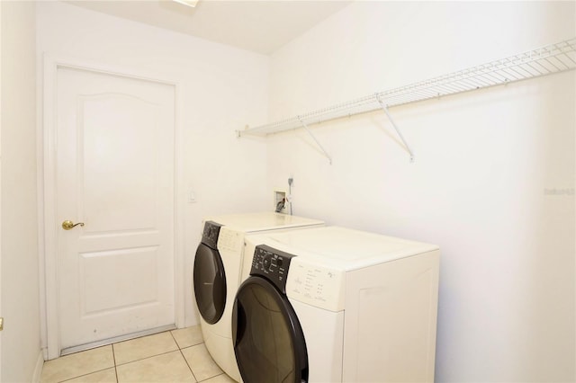 laundry area with washing machine and dryer and light tile patterned floors