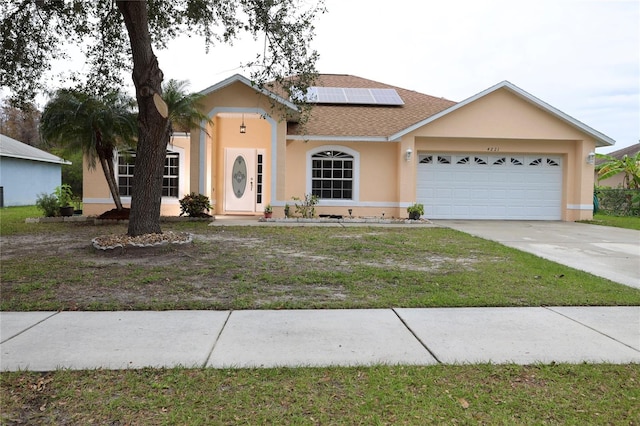 ranch-style house with solar panels, a front yard, and a garage