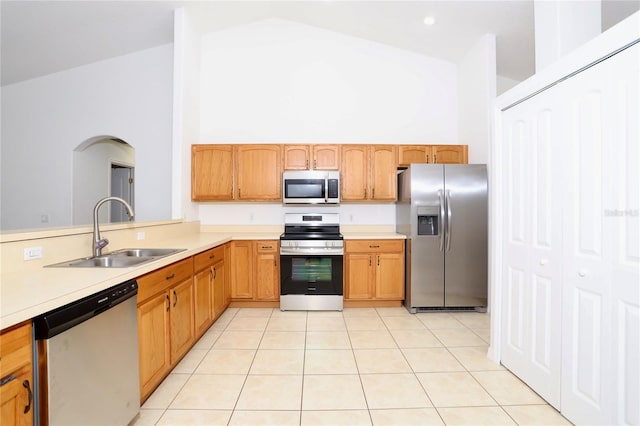 kitchen featuring high vaulted ceiling, appliances with stainless steel finishes, sink, and light tile patterned flooring