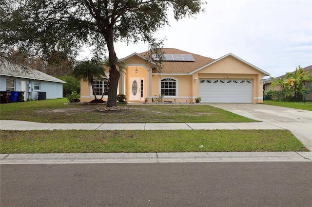 ranch-style house featuring solar panels, a front lawn, a garage, and central AC unit