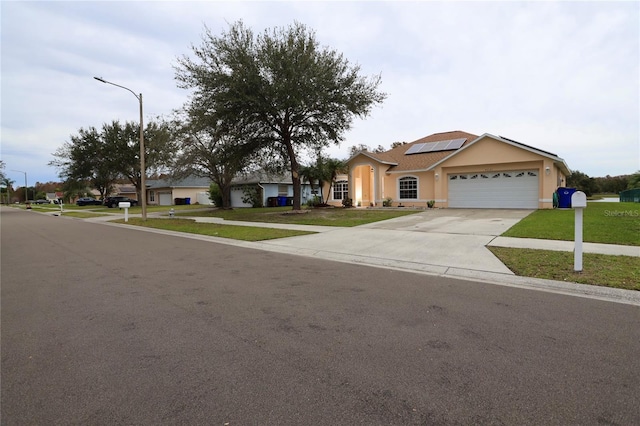 ranch-style home featuring a garage, a front lawn, and solar panels