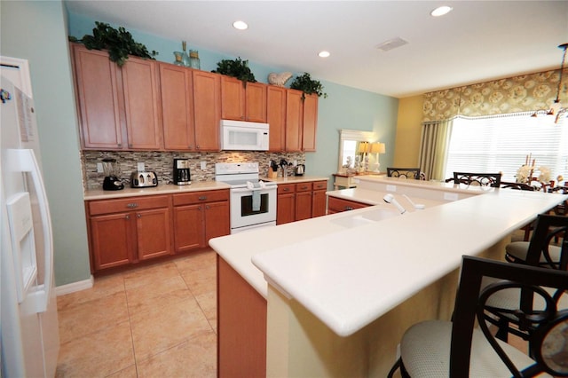 kitchen featuring tasteful backsplash, white appliances, a breakfast bar, and sink