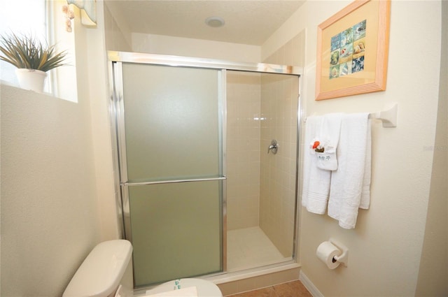 bathroom featuring toilet and a shower with door