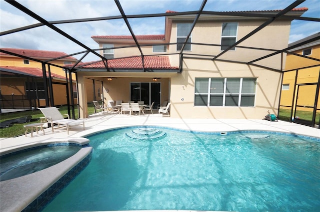 rear view of property with a swimming pool with hot tub, a lanai, and a patio area