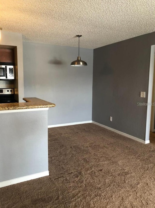 kitchen with dark colored carpet, appliances with stainless steel finishes, a textured ceiling, and decorative light fixtures