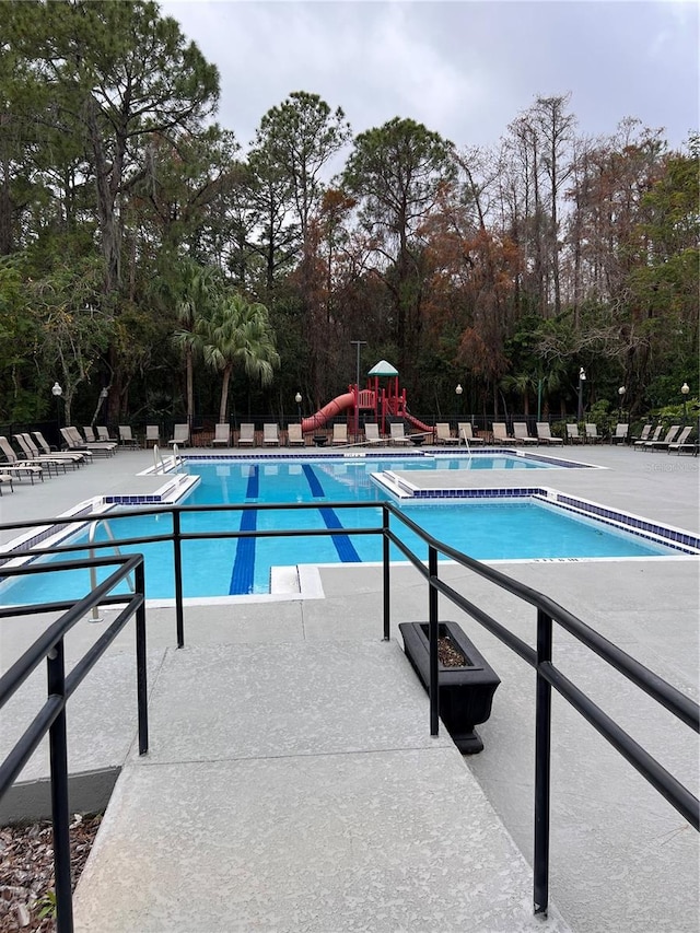 view of swimming pool featuring a playground and a patio area