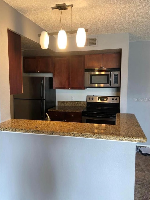 kitchen with stainless steel appliances, hanging light fixtures, stone countertops, and a textured ceiling