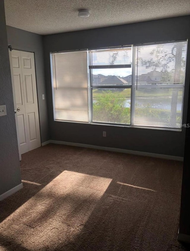 carpeted empty room featuring a textured ceiling