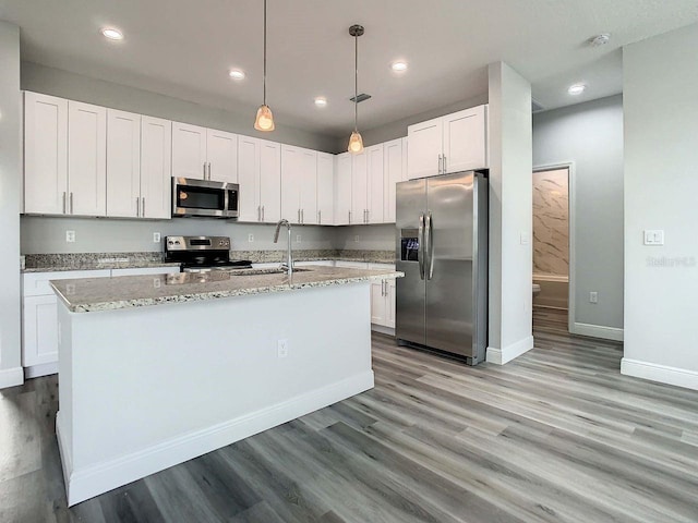 kitchen featuring appliances with stainless steel finishes, white cabinets, wood-type flooring, and a kitchen island with sink