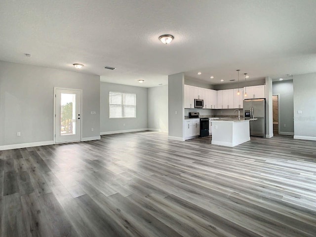 unfurnished living room featuring sink, wood-type flooring, and a textured ceiling