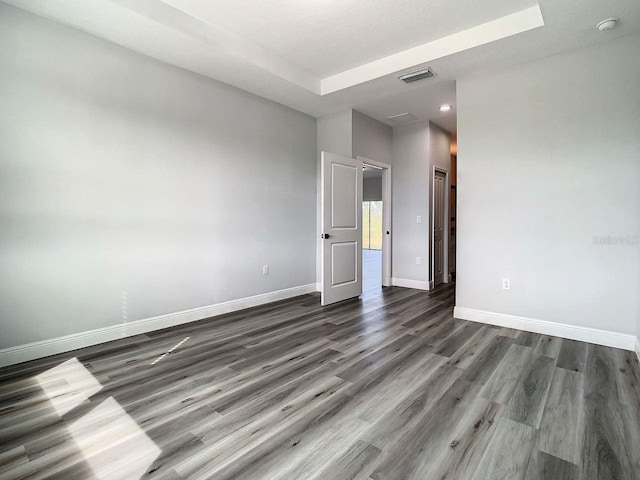 empty room with hardwood / wood-style flooring and a tray ceiling