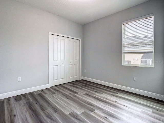 unfurnished bedroom with multiple windows, a closet, and hardwood / wood-style floors