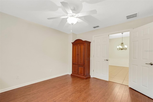 unfurnished bedroom featuring light wood-type flooring and ceiling fan with notable chandelier