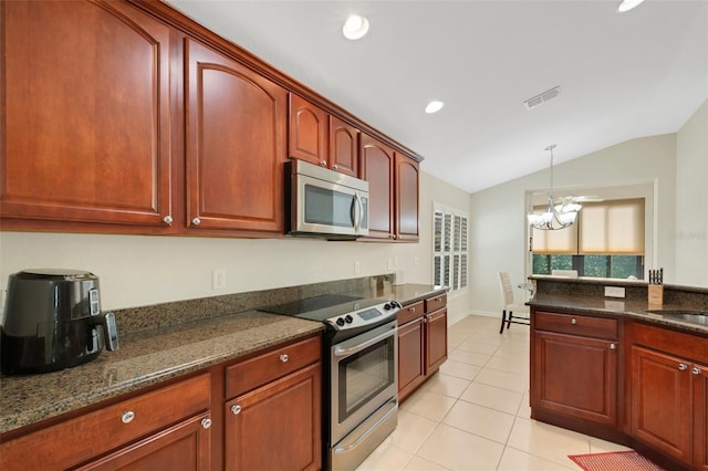 kitchen featuring lofted ceiling, light tile flooring, stainless steel appliances, a chandelier, and pendant lighting