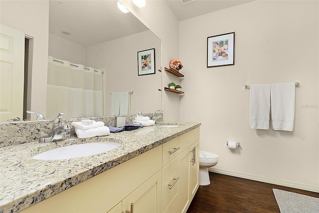 bathroom with oversized vanity, hardwood / wood-style floors, toilet, and dual sinks