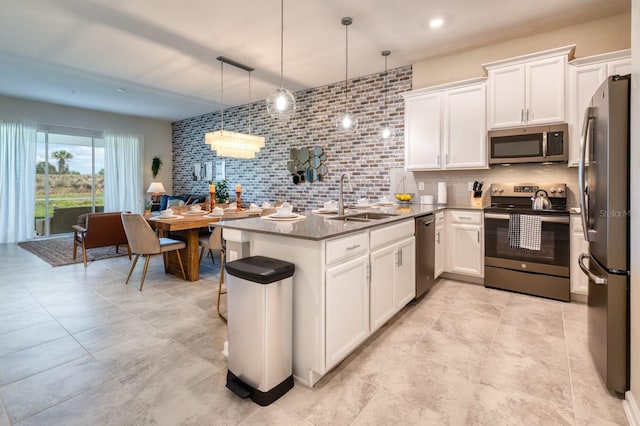 kitchen featuring kitchen peninsula, white cabinetry, sink, stainless steel appliances, and pendant lighting