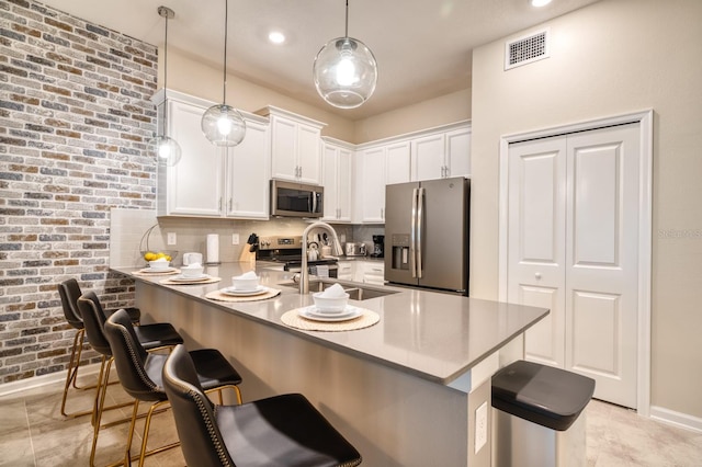 kitchen featuring a breakfast bar, hanging light fixtures, light tile flooring, and stainless steel appliances