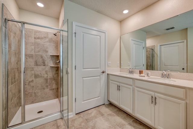 bathroom with large vanity, dual sinks, tile floors, and walk in shower