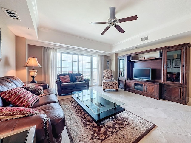 living room with ceiling fan, light tile patterned floors, ornamental molding, and a tray ceiling