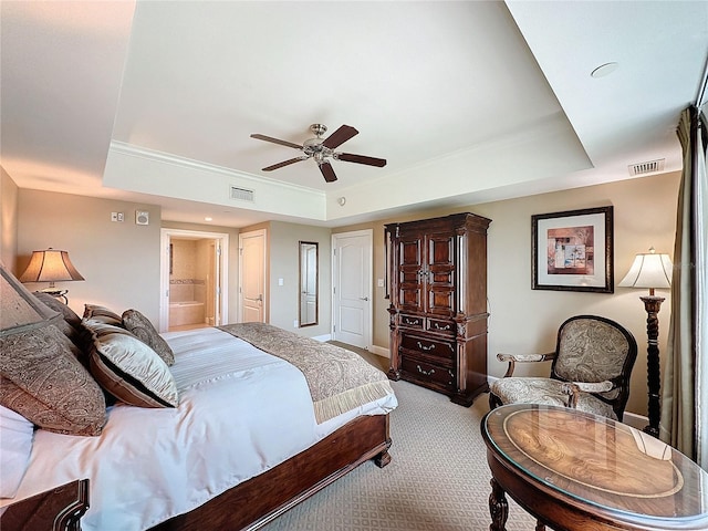 bedroom featuring a tray ceiling, ensuite bath, ceiling fan, and light colored carpet