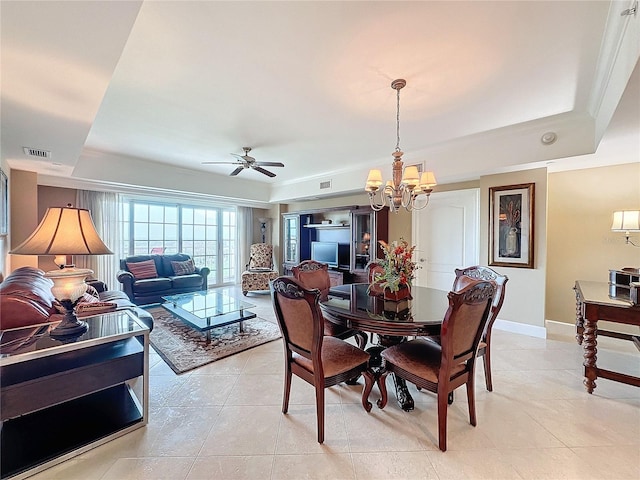 dining room featuring ceiling fan with notable chandelier, light tile patterned flooring, crown molding, and a tray ceiling