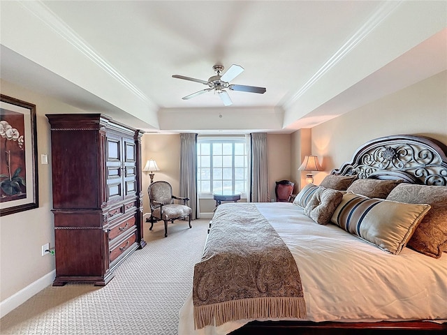 carpeted bedroom with a raised ceiling, ceiling fan, and ornamental molding