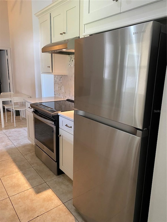 kitchen featuring backsplash, stainless steel appliances, light tile floors, and wall chimney exhaust hood