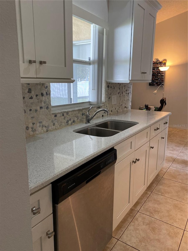 kitchen featuring light stone counters, white cabinets, sink, and stainless steel dishwasher