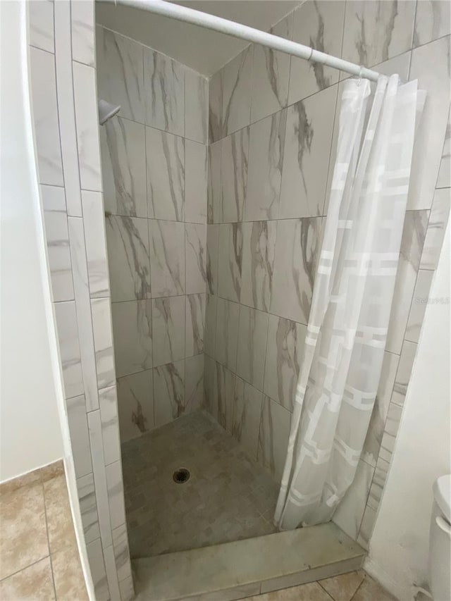 bathroom featuring curtained shower, toilet, and tile flooring