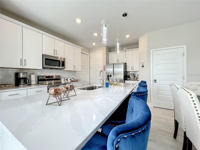 kitchen featuring white cabinets, a breakfast bar, hanging light fixtures, and stainless steel appliances