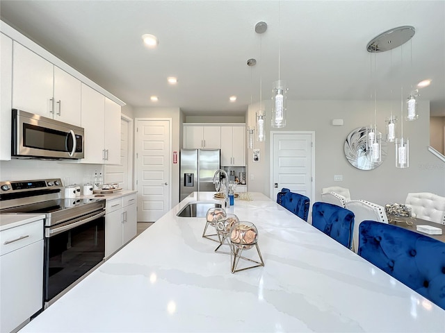 kitchen featuring decorative light fixtures, backsplash, a kitchen breakfast bar, appliances with stainless steel finishes, and white cabinets