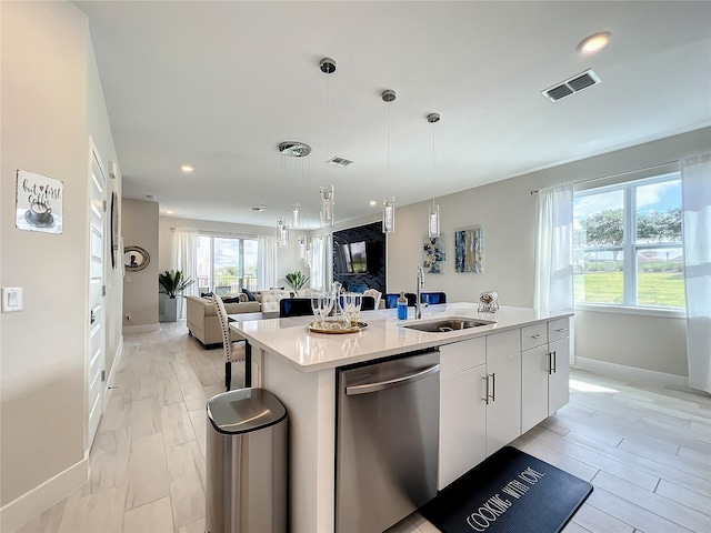 kitchen featuring a kitchen island with sink, pendant lighting, sink, stainless steel dishwasher, and white cabinetry