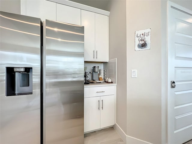 kitchen with tasteful backsplash, stainless steel refrigerator with ice dispenser, white cabinets, and light hardwood / wood-style flooring