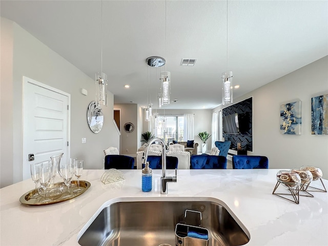 kitchen featuring light stone countertops, decorative light fixtures, and sink