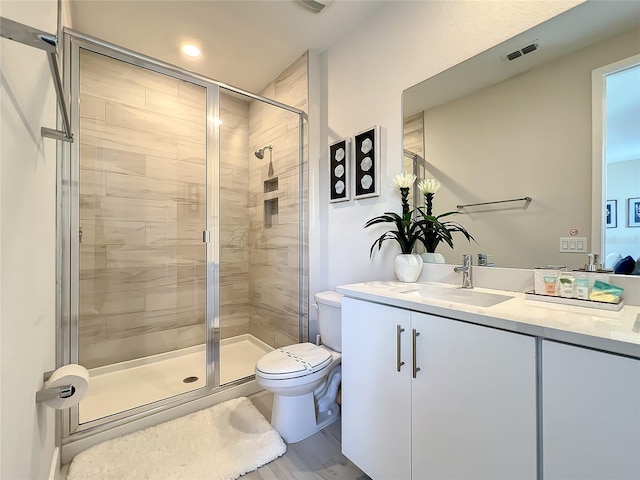 bathroom featuring toilet, vanity, a shower with shower door, and wood-type flooring