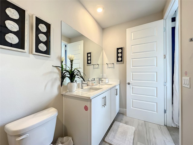 bathroom with toilet, vanity, and hardwood / wood-style flooring