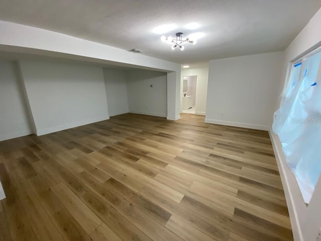 basement featuring built in desk, wood-type flooring, and an inviting chandelier