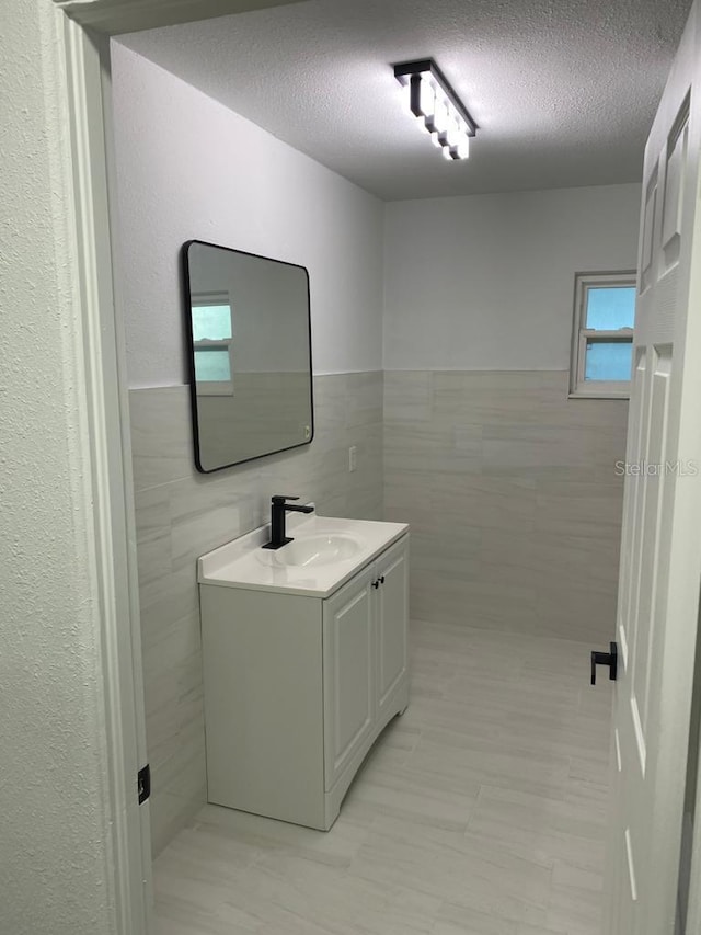 bathroom with vanity, tile walls, and a textured ceiling